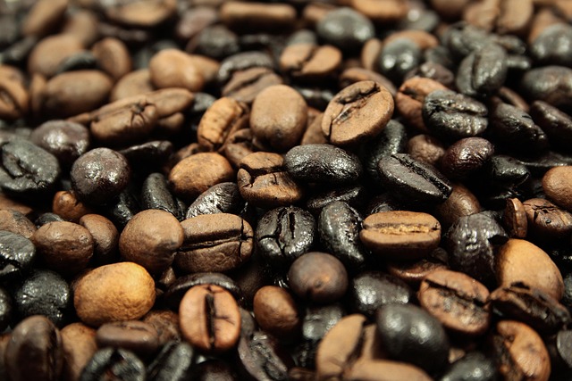 Close-up of a professional Probat coffee roaster drum with freshly roasted organic beans tumbling into the cooling tray with golden warm light and rising steam